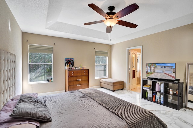 bedroom with a raised ceiling, ceiling fan, and a textured ceiling