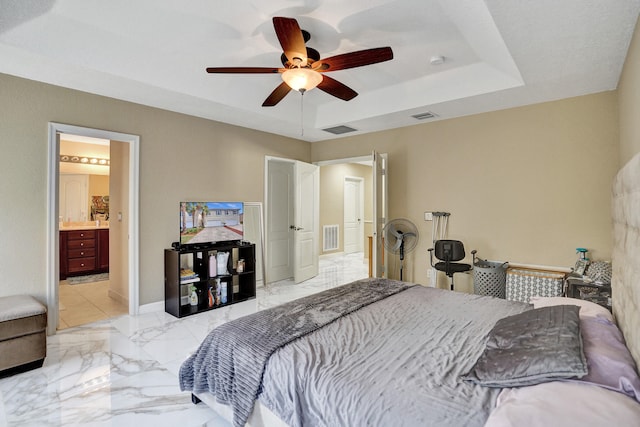 bedroom with a raised ceiling, ensuite bath, and ceiling fan