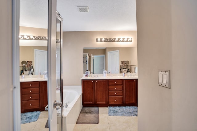 bathroom featuring tile patterned floors, vanity, a tub, and a textured ceiling