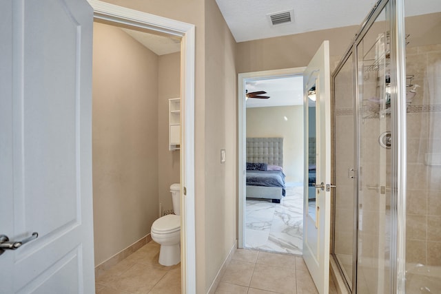 bathroom with tile patterned floors, a textured ceiling, toilet, and a shower with door