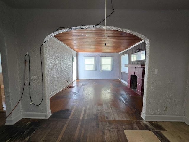 unfurnished living room with dark hardwood / wood-style floors, wood ceiling, and a tile fireplace