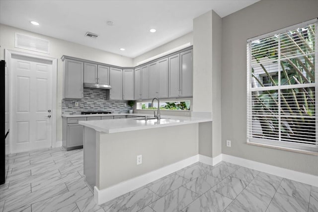 kitchen featuring gray cabinets, gas stovetop, kitchen peninsula, and sink