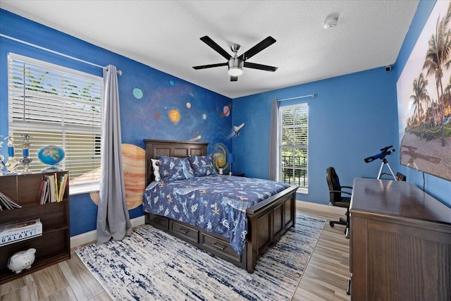 bedroom featuring ceiling fan, light hardwood / wood-style flooring, and a textured ceiling