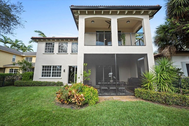 back of house featuring a lawn, a sunroom, and a balcony