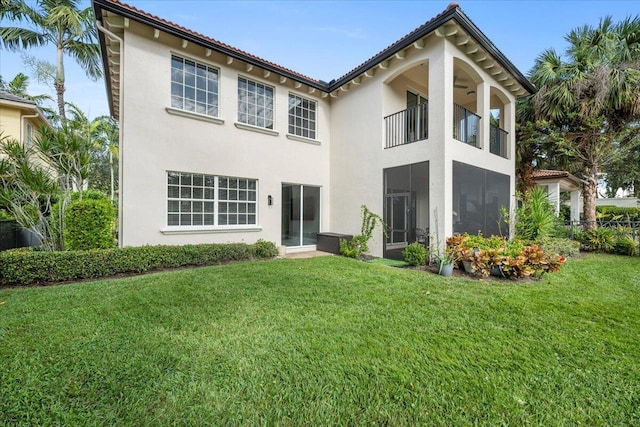 rear view of property featuring a balcony and a yard