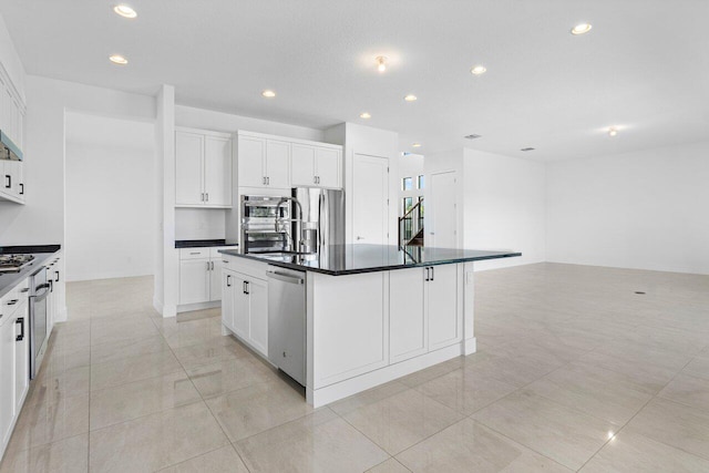 kitchen with a kitchen island with sink, white cabinets, and stainless steel appliances