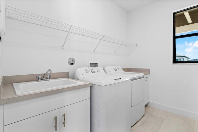 laundry area with cabinets, separate washer and dryer, and sink