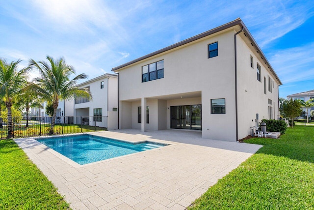 rear view of property featuring a fenced in pool, a patio area, and a yard