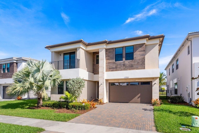 view of front of home featuring a garage, a balcony, and a front yard