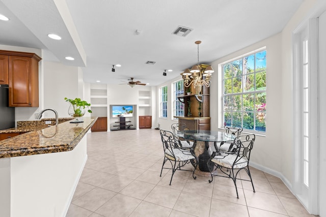 dining area featuring built in shelves, ceiling fan with notable chandelier, light tile patterned flooring, and sink