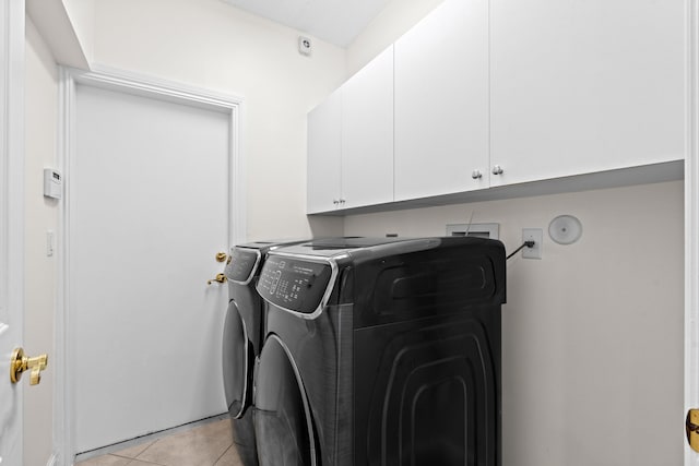 laundry area with light tile patterned flooring, cabinets, and washer and clothes dryer