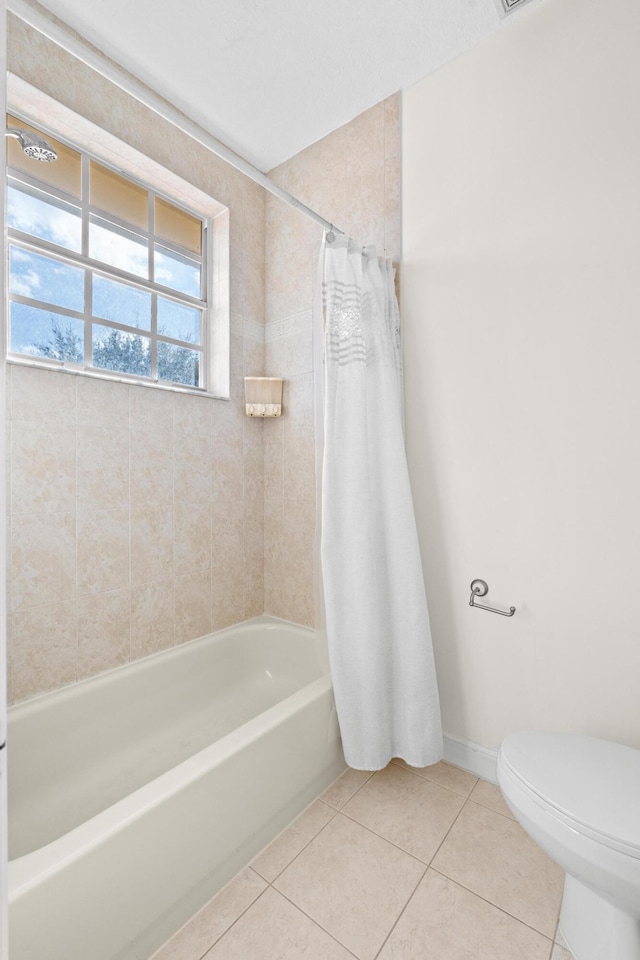 bathroom with tile patterned flooring, shower / tub combo, and toilet