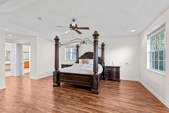 bedroom featuring multiple windows, hardwood / wood-style floors, connected bathroom, and ceiling fan