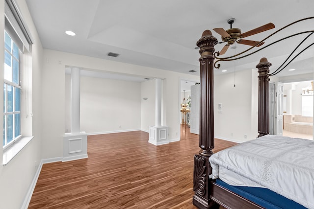 bedroom with dark hardwood / wood-style flooring, multiple windows, ensuite bathroom, and ornate columns