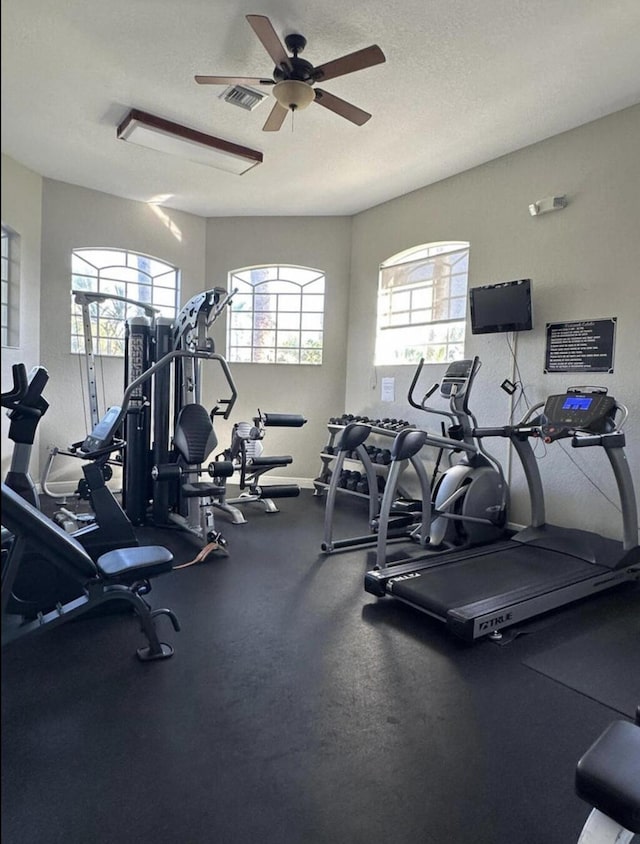 gym featuring ceiling fan and a textured ceiling