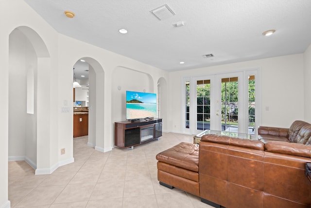 tiled living room featuring french doors and a textured ceiling