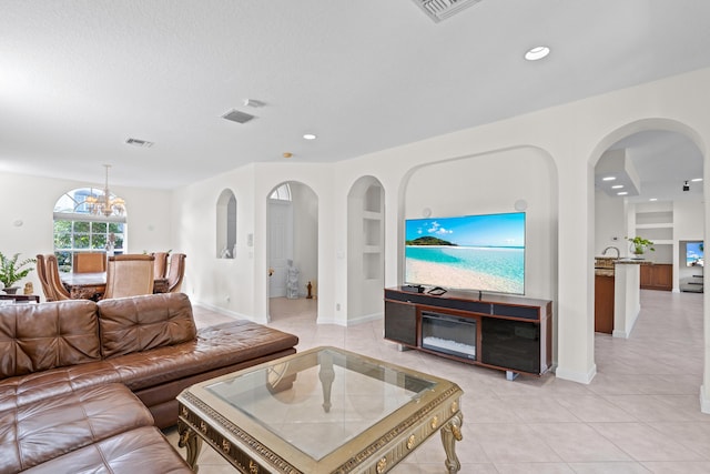 tiled living room featuring a notable chandelier, a textured ceiling, and built in shelves