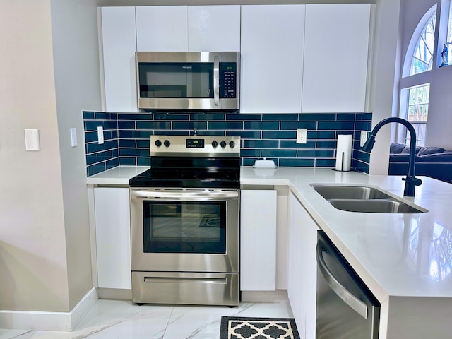 kitchen featuring stainless steel appliances, white cabinets, tasteful backsplash, and sink