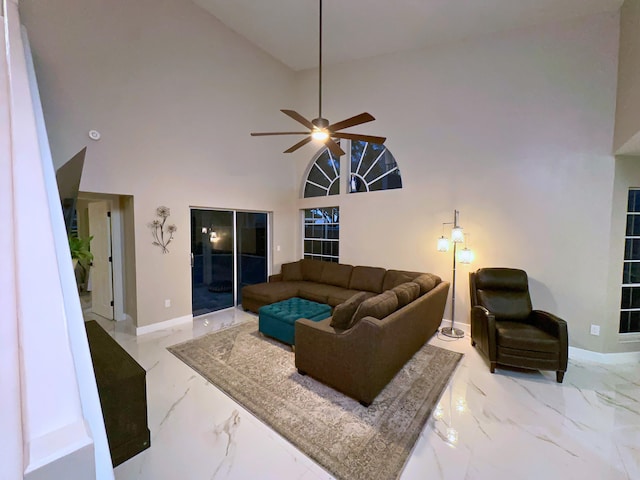 living area featuring a ceiling fan, baseboards, marble finish floor, and high vaulted ceiling