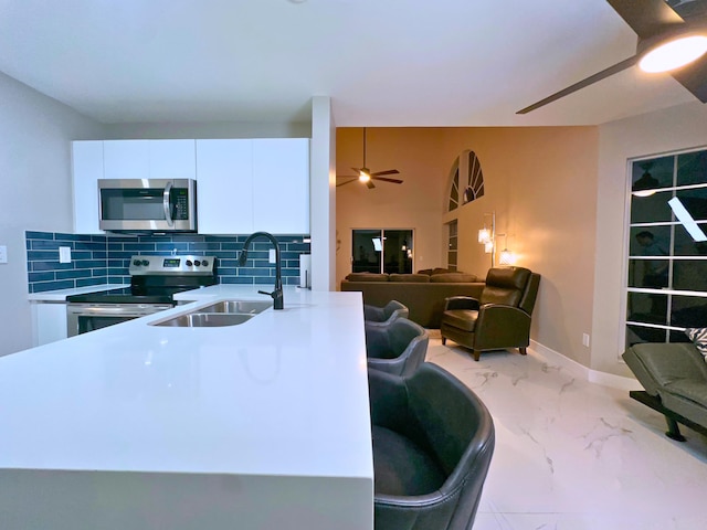 kitchen featuring tasteful backsplash, ceiling fan, sink, stainless steel appliances, and white cabinets