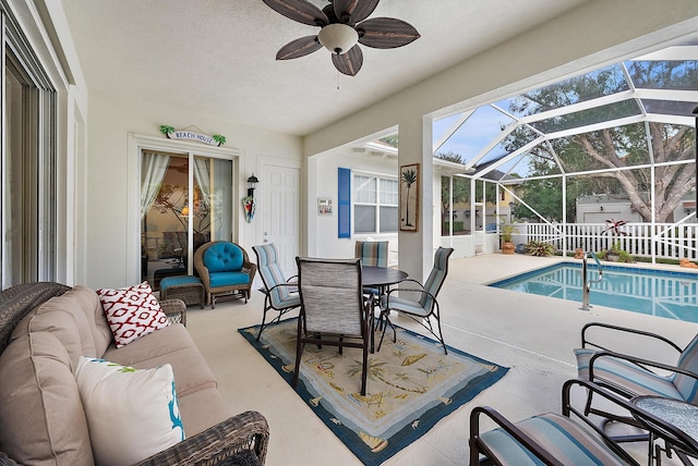 view of swimming pool with ceiling fan, a lanai, an outdoor living space, and a patio