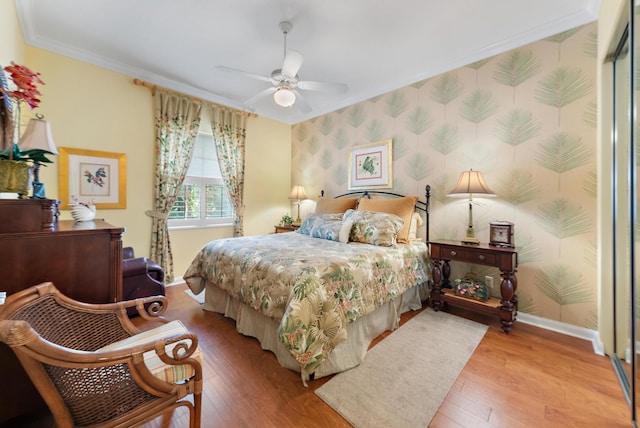 bedroom featuring ceiling fan, ornamental molding, a closet, and light hardwood / wood-style flooring