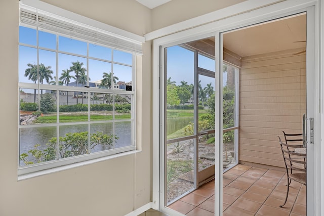 doorway to outside with a water view, light tile patterned floors, and a healthy amount of sunlight