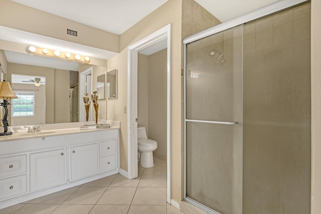 bathroom with ceiling fan, tile patterned floors, toilet, a shower with door, and vanity