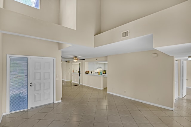 tiled foyer with ceiling fan and a towering ceiling