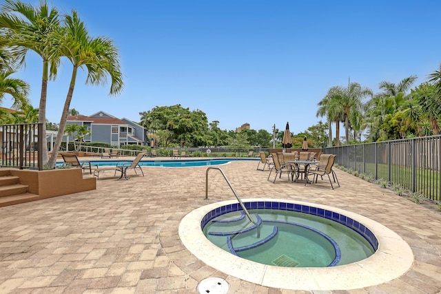 view of swimming pool with a hot tub and a patio area