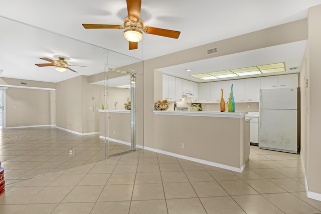 kitchen featuring kitchen peninsula, white cabinets, light tile patterned floors, and white refrigerator