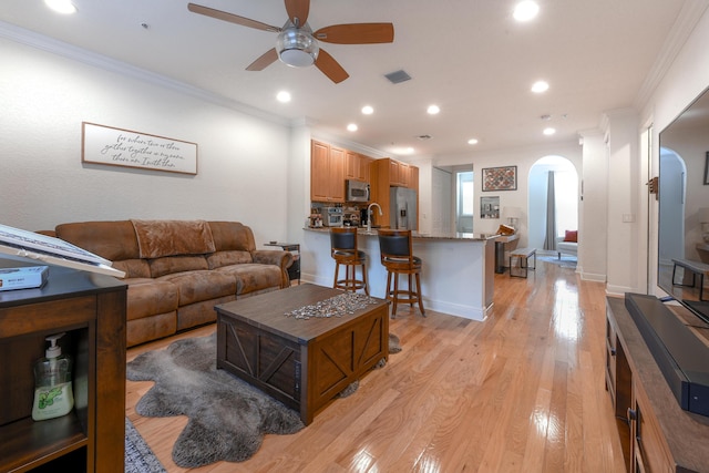 living room featuring crown molding, light hardwood / wood-style flooring, ceiling fan, and sink