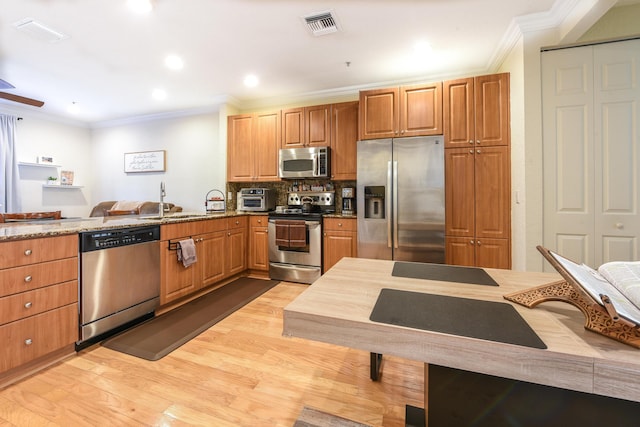 kitchen with sink, light hardwood / wood-style floors, light stone counters, kitchen peninsula, and stainless steel appliances