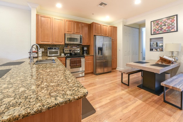 kitchen with light stone countertops, sink, stainless steel appliances, light hardwood / wood-style floors, and ornamental molding