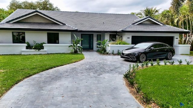 ranch-style home featuring a garage, driveway, a front lawn, and a tiled roof