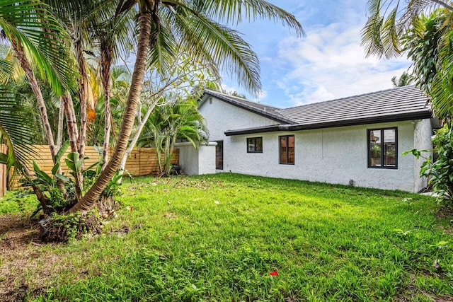 view of home's exterior featuring a lawn, fence, and stucco siding