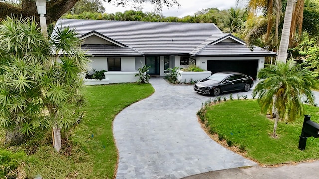 ranch-style house with driveway, a garage, a tile roof, a front lawn, and stucco siding