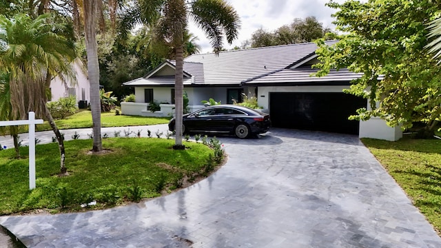 ranch-style house with a garage, a tile roof, decorative driveway, and a front yard