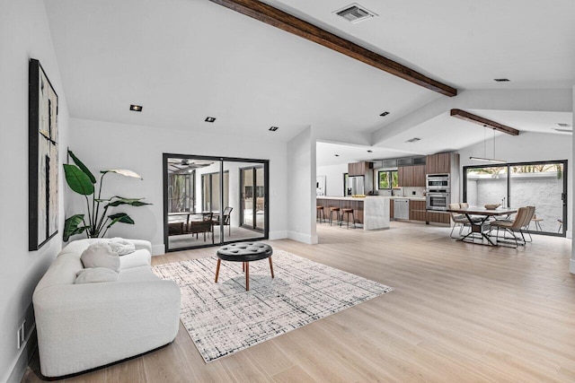 living room featuring vaulted ceiling with beams and light hardwood / wood-style floors