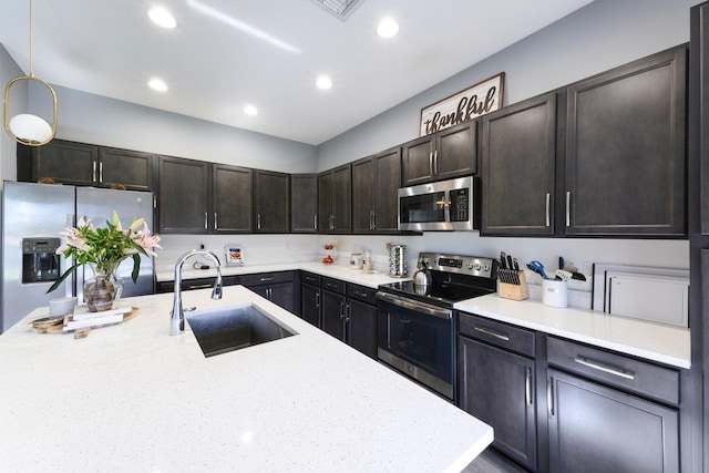 kitchen with dark brown cabinetry, light stone countertops, sink, pendant lighting, and appliances with stainless steel finishes