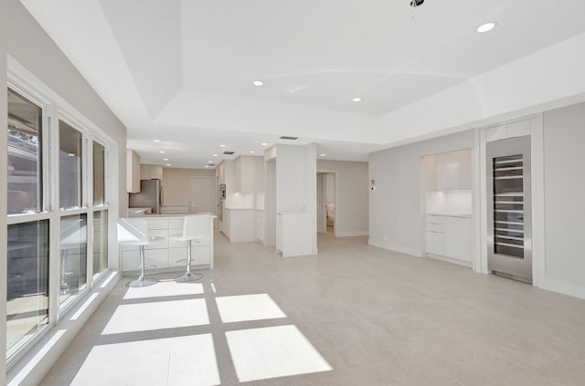 unfurnished living room featuring beverage cooler and a raised ceiling