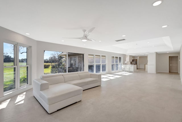 living room featuring ceiling fan and a tray ceiling