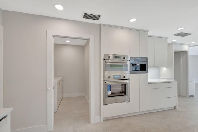 kitchen featuring separate washer and dryer, stainless steel double oven, and white cabinets