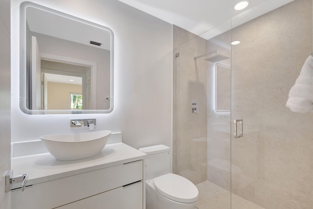 bathroom featuring vanity, toilet, and a shower with shower door