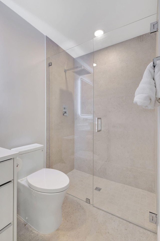 bathroom featuring vanity, toilet, and a shower with door