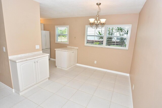 1225 NW 21st St Unit 3406, Stuart, FL 34994 - spare room featuring a chandelier, baseboards, light tile patterned floors, and a textured ceiling