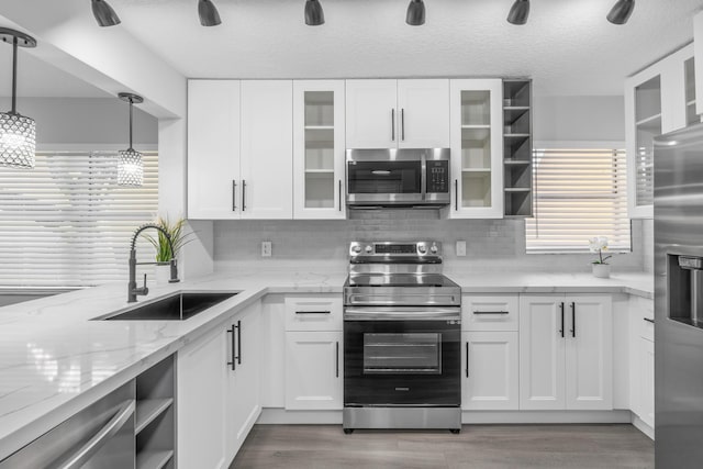 kitchen with appliances with stainless steel finishes, tasteful backsplash, sink, decorative light fixtures, and white cabinetry