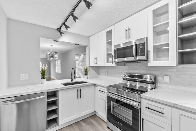 kitchen featuring a textured ceiling, stainless steel appliances, white cabinetry, and sink