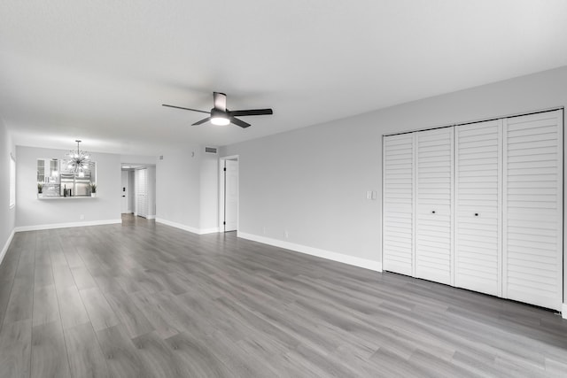 unfurnished living room featuring hardwood / wood-style flooring and ceiling fan with notable chandelier