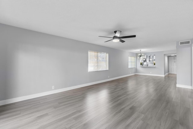 spare room featuring hardwood / wood-style flooring and ceiling fan with notable chandelier